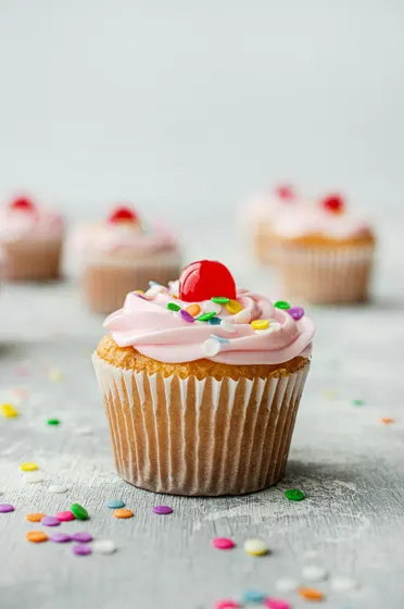 Frosted cupcake with sprinkles and a cherry